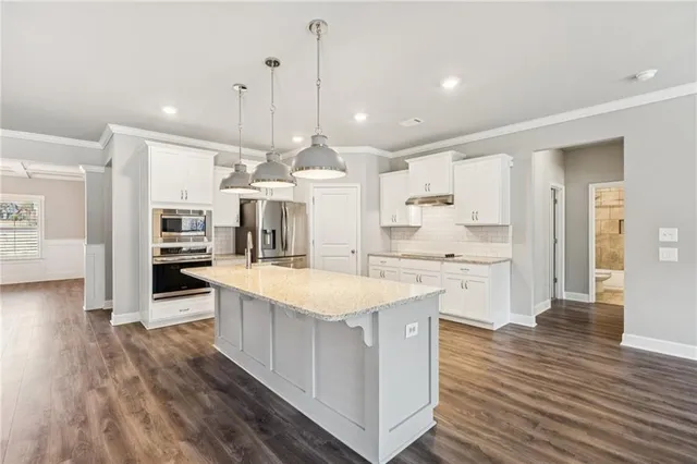 a large kitchen with stainless steel appliances kitchen island a large counter top and a wooden floors