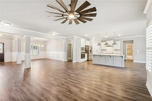 a view of an empty room with wooden floor and a ceiling fan