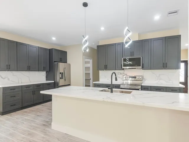 a kitchen with kitchen island a sink stainless steel appliances and cabinets