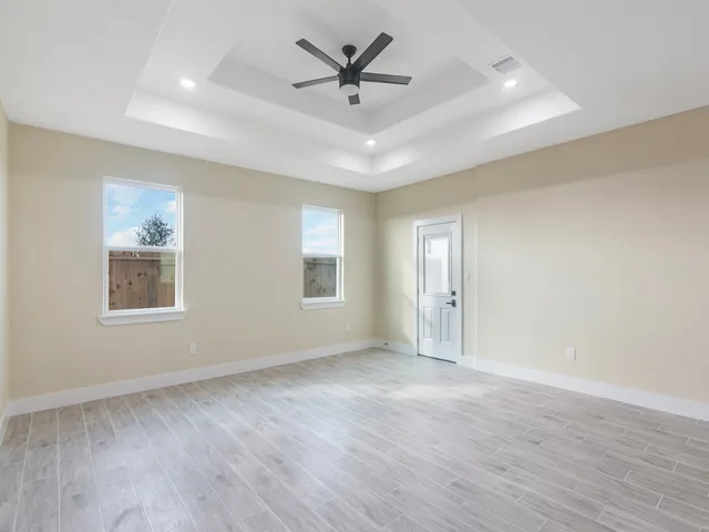 an empty room with wooden floor and windows