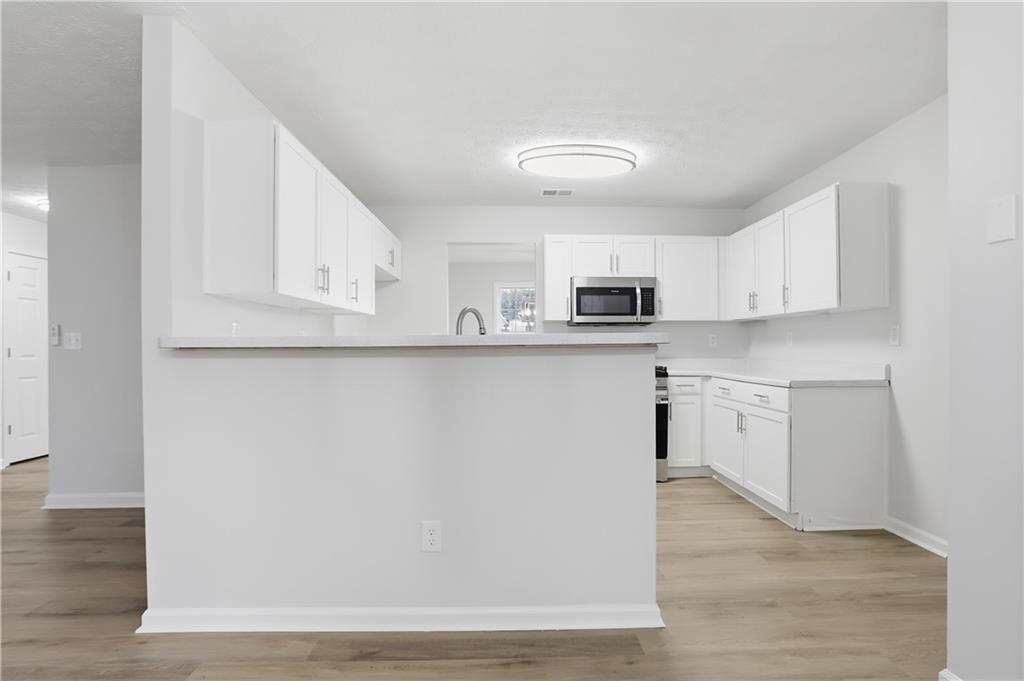 5556 Claridge Circle Stonecrest, GA 30038 - Photo 6 of 25 a kitchen with stainless steel appliances granite countertop a refrigerator a stove a sink and white cabinets with wooden floor
