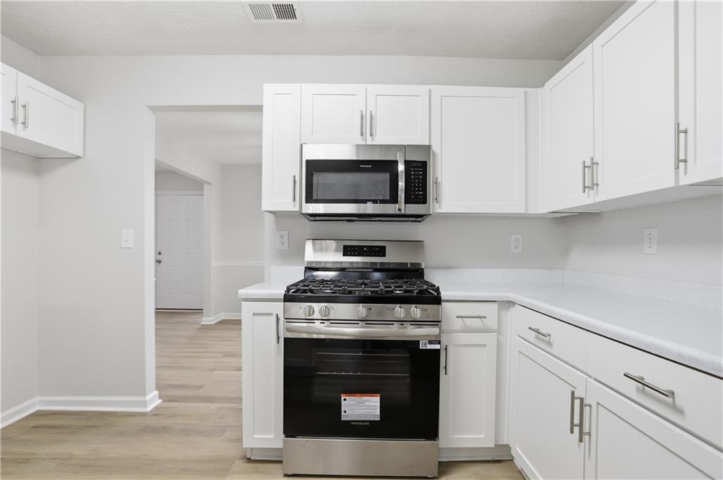 5556 Claridge Circle Stonecrest, GA 30038 - Photo 7 of 25 a kitchen with cabinets stainless steel appliances and a wooden floor