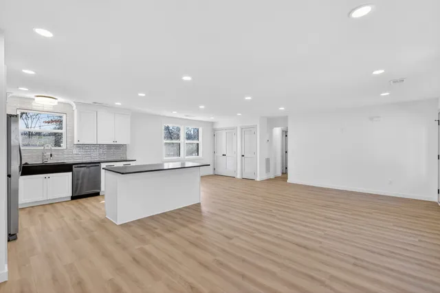 a large kitchen with stainless steel appliances granite countertop a large counter top a sink and a refrigerator