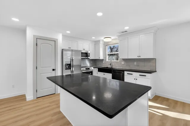 a kitchen with stainless steel appliances granite countertop a sink a stove and a center island