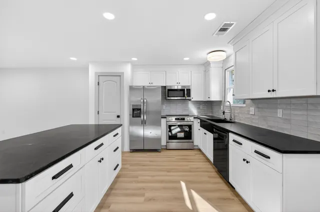 a large kitchen with stainless steel appliances granite countertop a stove a sink and a refrigerator