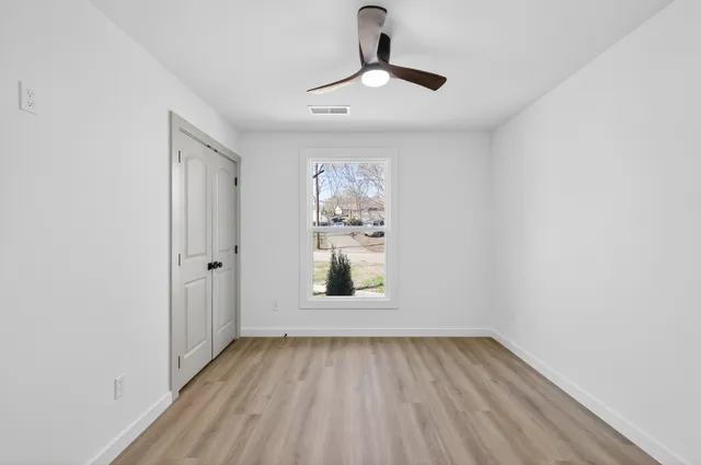 a view of empty room with window and wooden floor