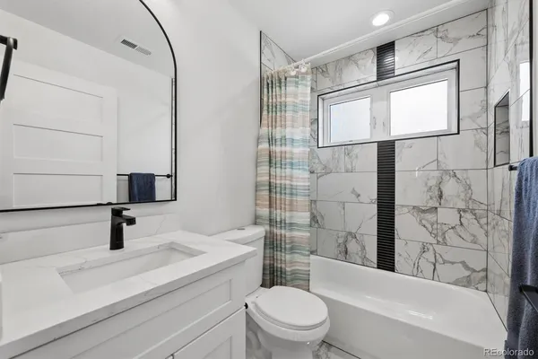a bathroom with a bathtub shower sink vanity and toilet