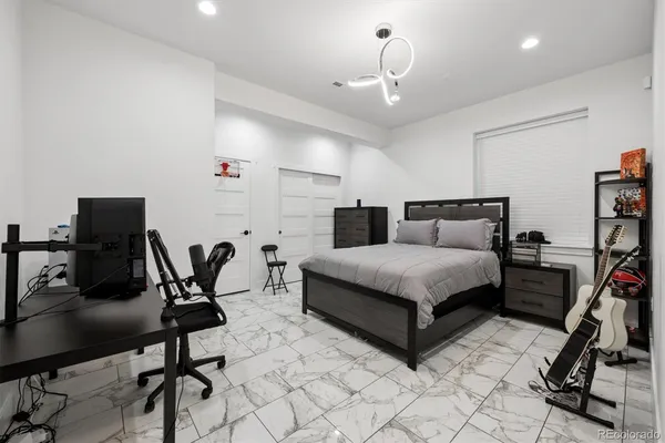 a bedroom with a bed a desk and chair with the wooden floor