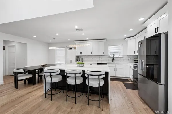 a kitchen with stainless steel appliances kitchen island granite countertop a table chairs sink and cabinets