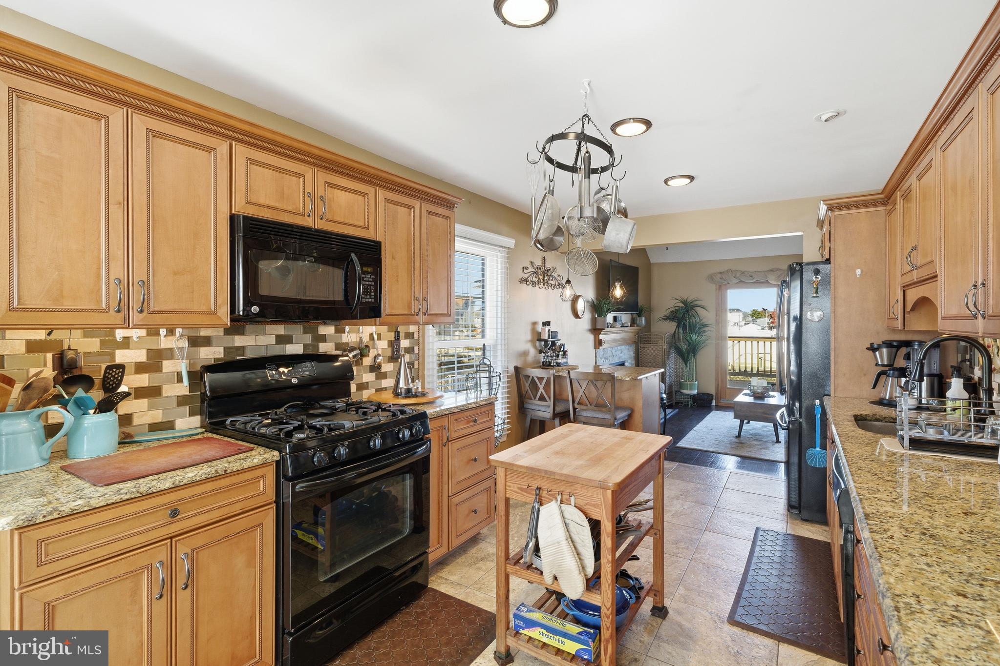 179 Bernard Drive Manahawkin, NJ 08050 - Photo 12 of 35 a kitchen with stainless steel appliances granite countertop a stove top oven a sink a dining table and chairs with wooden floor