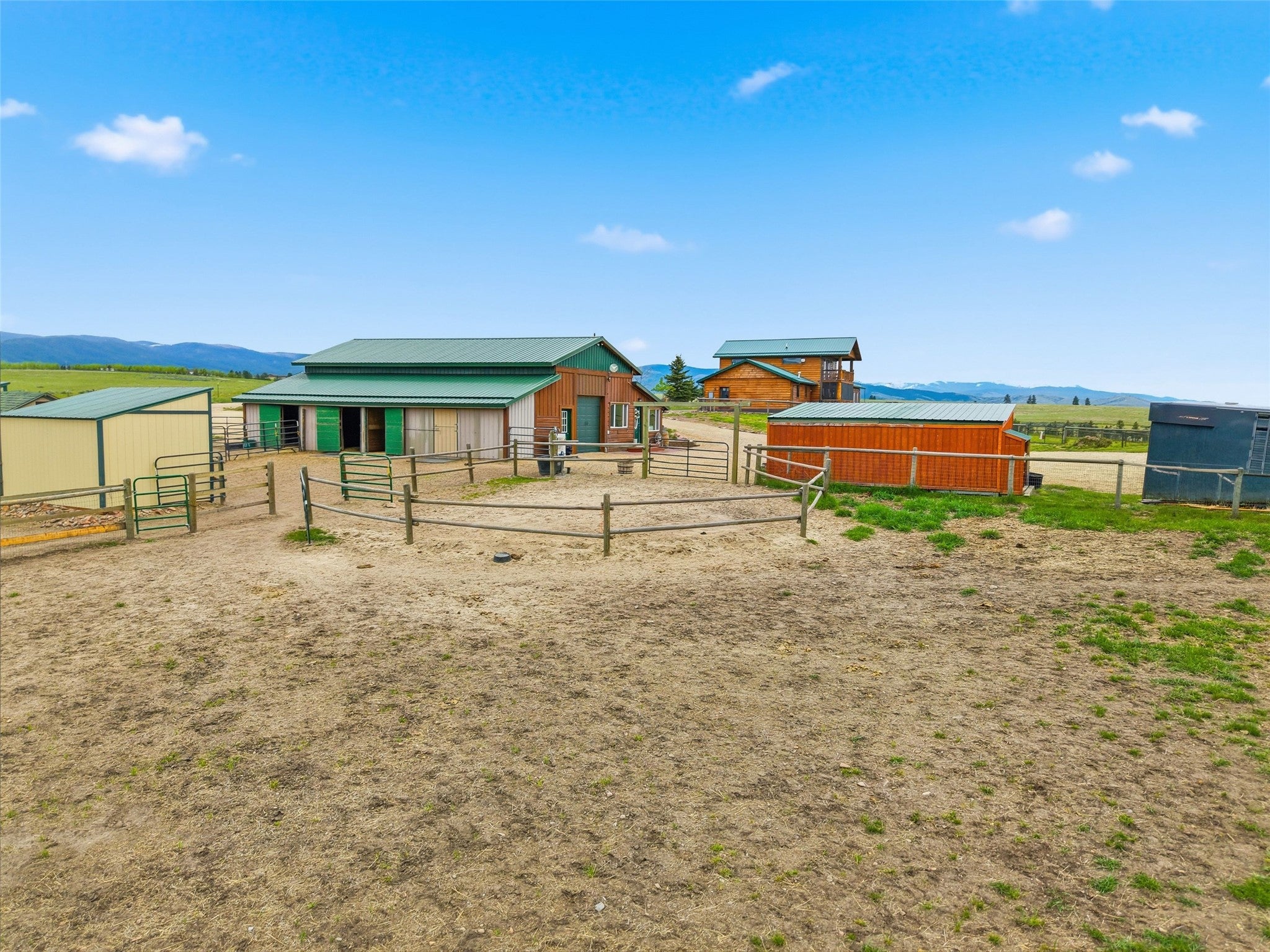 679 Hidden Valley Road North Florence, MT 59833 - Photo 68 of 85 Expansive outdoor area featuring multiple fenced enclosures, a large barn with a green metal roof and multiple stalls, and additional outbuildings