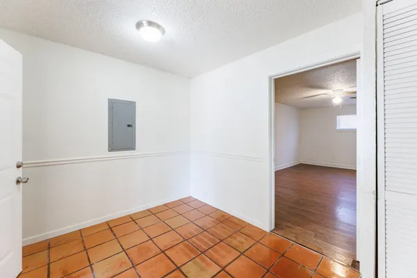 an empty room with wooden floor chandelier fan and windows