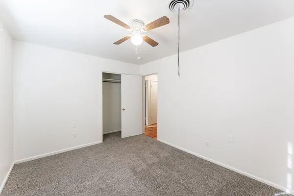 an empty room with ceiling fan and windows