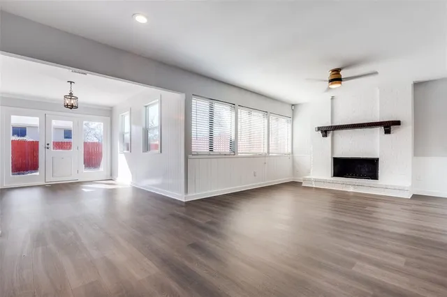 an empty room with wooden floor fireplace and windows