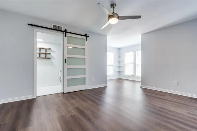an empty room with wooden floor closet and windows
