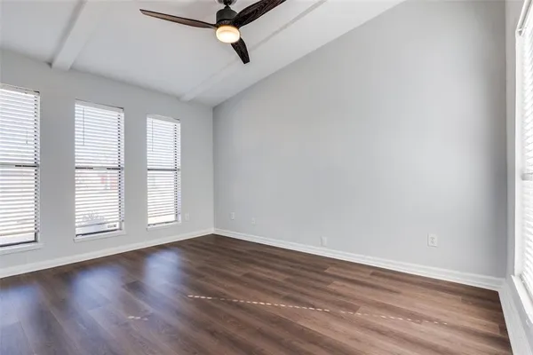 an empty room with wooden floor fan and windows
