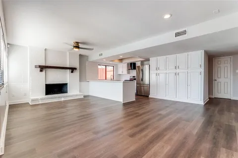 an empty room with wooden floor fireplace and windows