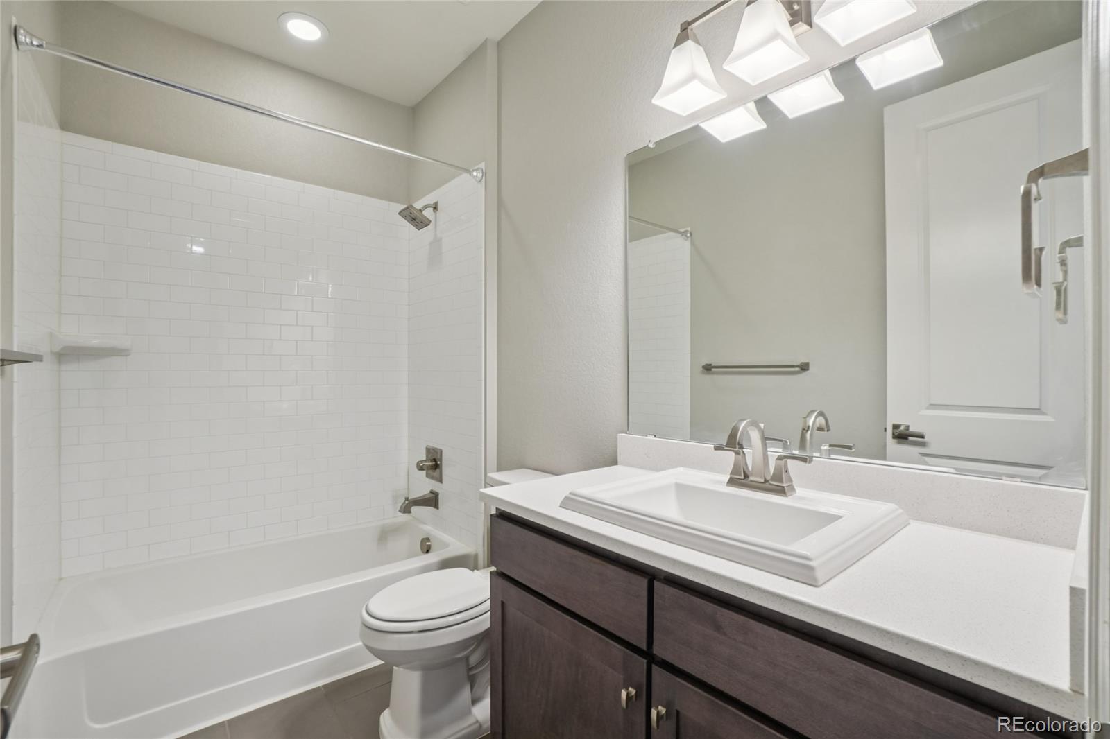 6523 Independence Street Frederick, CO 80516 - Photo 14 of 21 a bathroom with a sink a toilet a mirror and shower