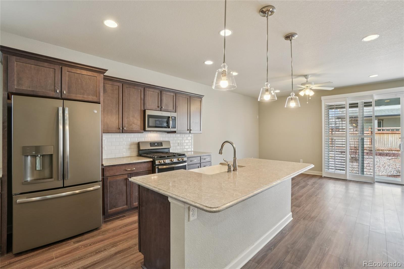 6523 Independence Street Frederick, CO 80516 - Photo 5 of 21 a kitchen with a sink a kitchen island a stove a refrigerator and a center island