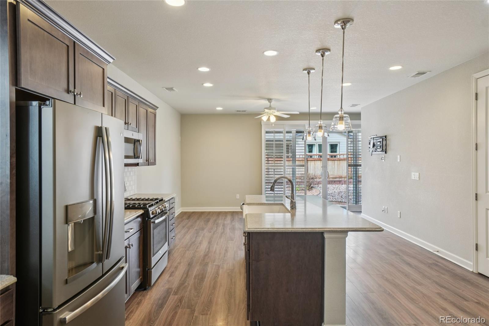 6523 Independence Street Frederick, CO 80516 - Photo 7 of 21 a kitchen with stainless steel appliances granite countertop a refrigerator a sink and wooden floor