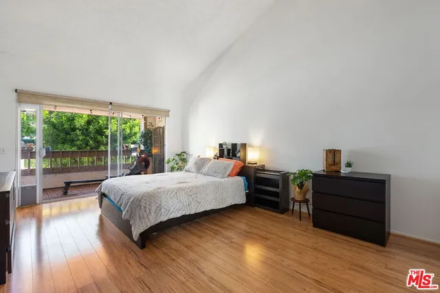 a spacious bedroom with a bed and wooden floor