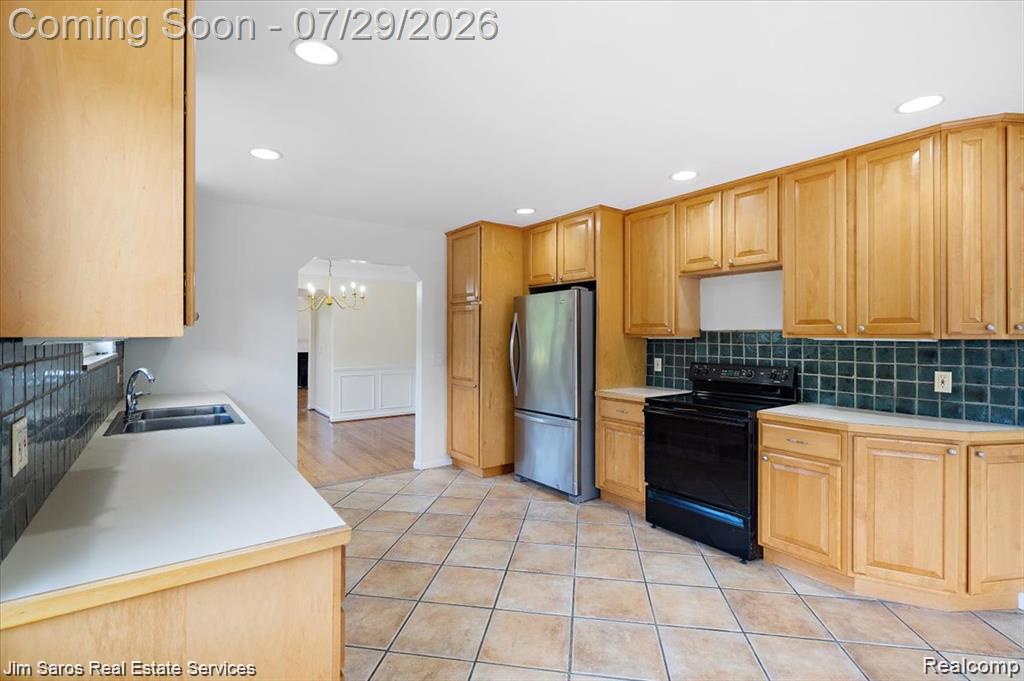 620 Neff Road Grosse Pointe, MI 48230 - Photo 7 of 14 Kitchen featuring extensive light wood cabinetry, light-toned countertops, a stainless steel refrigerator, and a black range