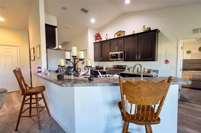 a view of a kitchen with kitchen island granite countertop a table chairs microwave and sink
