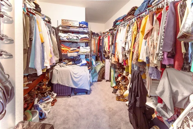 a view of walk in closet with clothes and shoes