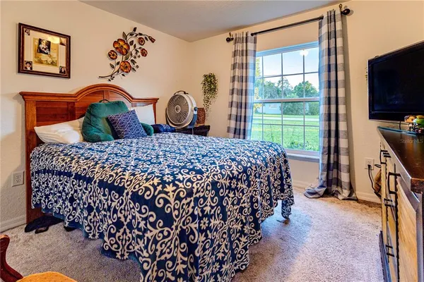 a bedroom with a bed window and a flat tv screen in it