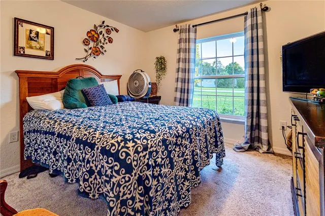 a bedroom with a bed window and a flat tv screen in it