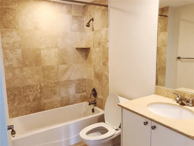 a bathroom with a granite countertop bathtub sink vanity mirror and toilet