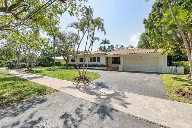 a view of a house with a yard and palm trees