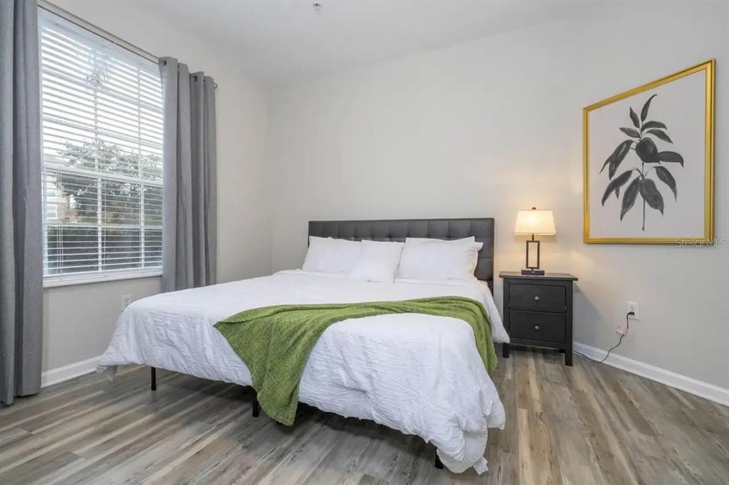 5025 Shoreway Loop, Unit 10703 Orlando, FL 32819 - Photo 13 of 53 a bedroom with a bed and wooden floor