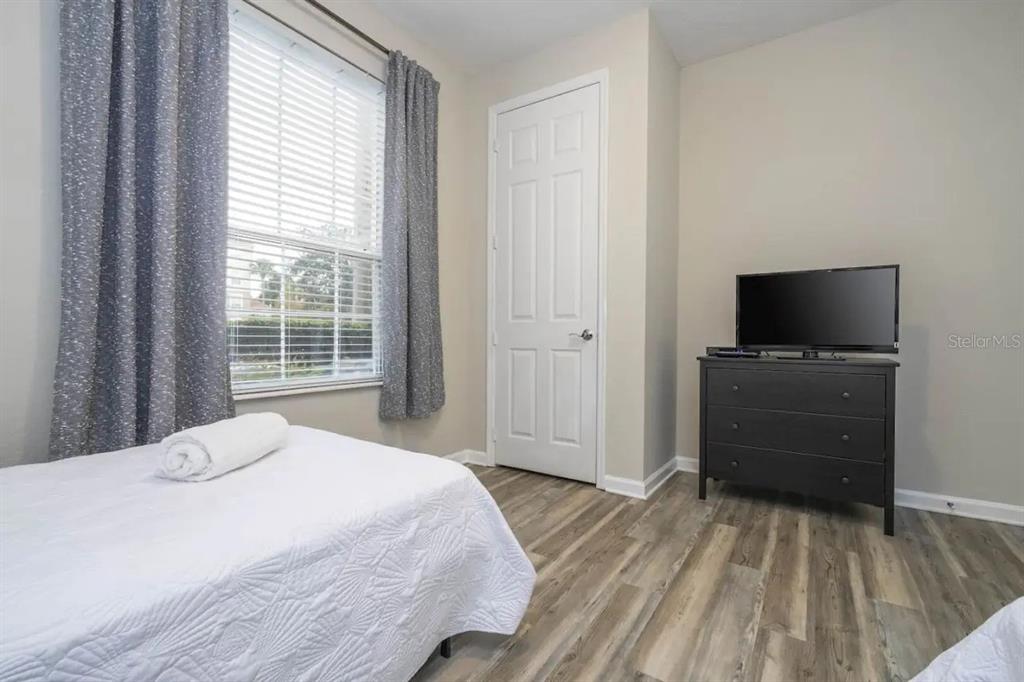 5025 Shoreway Loop, Unit 10703 Orlando, FL 32819 - Photo 23 of 53 a bedroom with a bed and a flat tv screen on a dresser