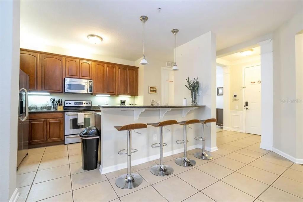 5025 Shoreway Loop, Unit 10703 Orlando, FL 32819 - Photo 3 of 53 a kitchen with stainless steel appliances kitchen island granite countertop a stove a sink and a refrigerator
