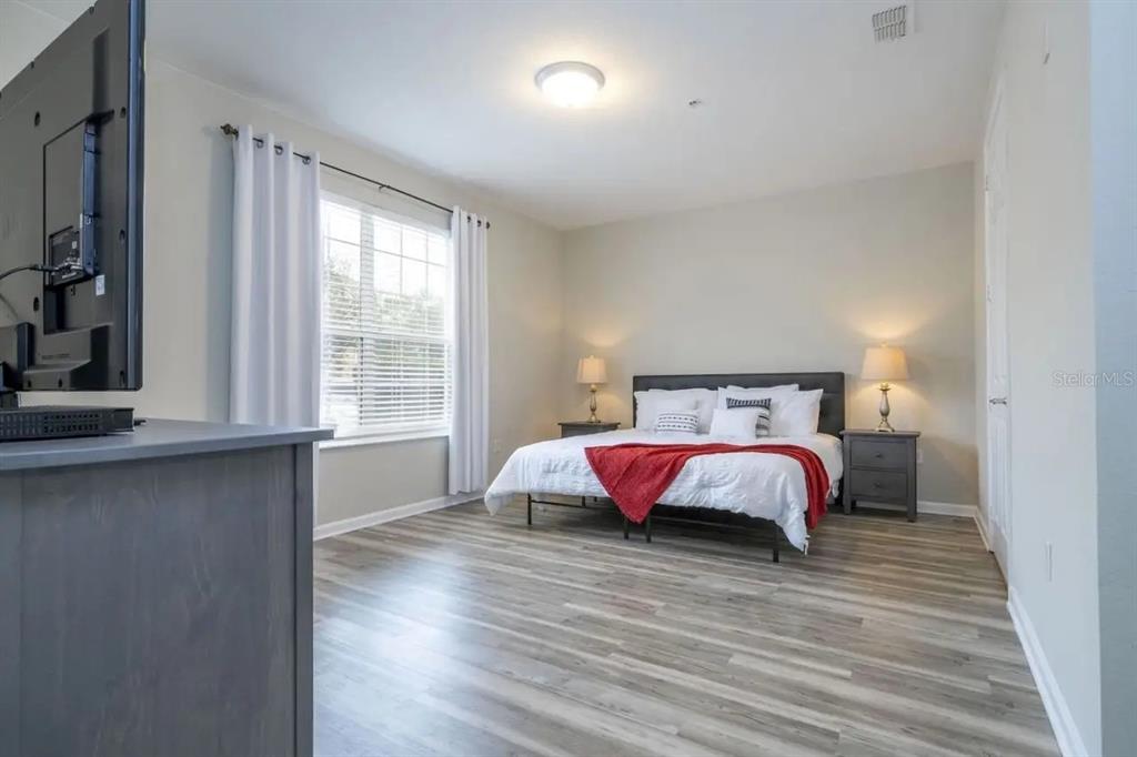 5025 Shoreway Loop, Unit 10703 Orlando, FL 32819 - Photo 9 of 53 a spacious bedroom with a bed and wooden floor
