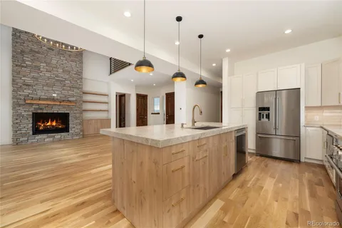 a kitchen with stainless steel appliances granite countertop a sink a oven a refrigerator and a wooden floor
