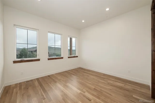 an empty room with wooden floor and windows