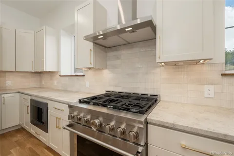 a kitchen with stainless steel appliances granite countertop a sink a stove and a wooden floors