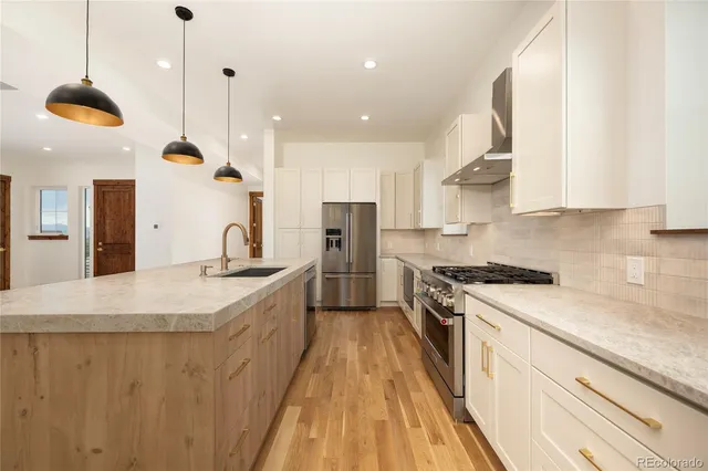 a kitchen with stainless steel appliances granite countertop a sink a stove and a refrigerator