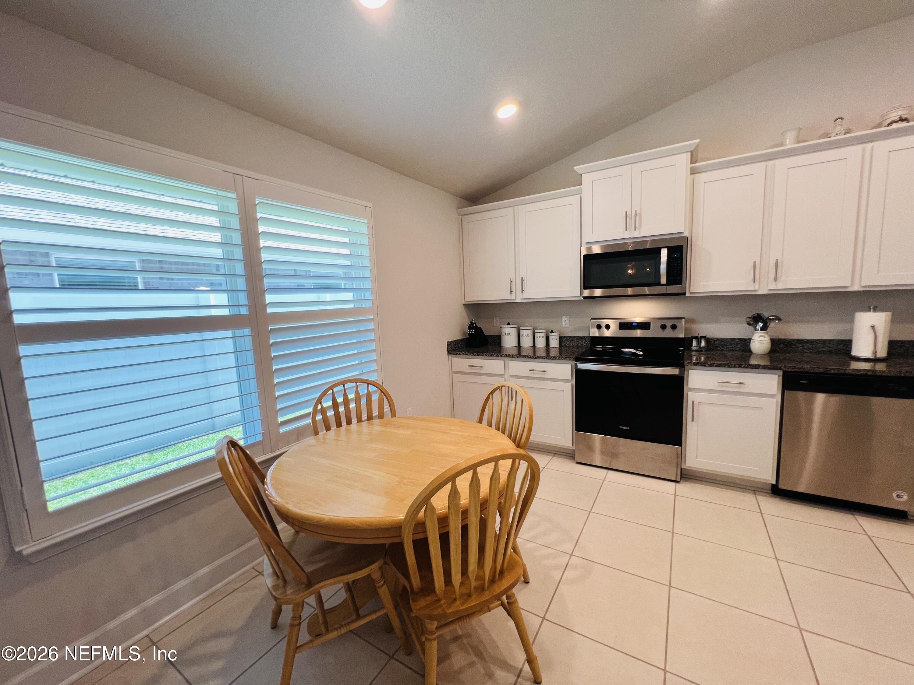 2 Rivertown Road Palm Coast, FL 32137 - Photo 39 of 80 a kitchen with stainless steel appliances granite countertop a stove a sink a microwave dining table and chairs
