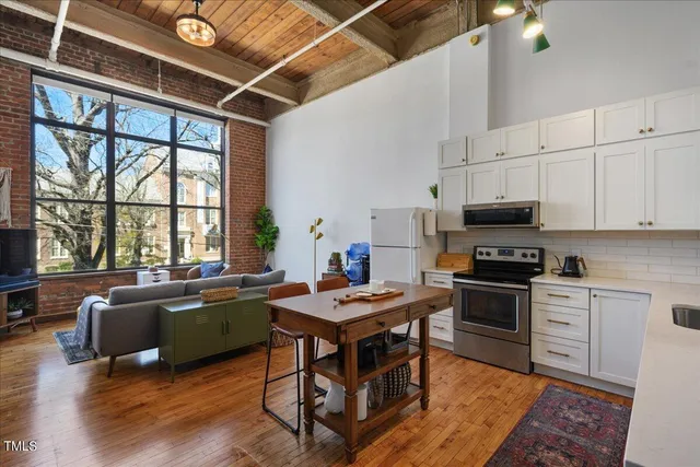 a kitchen with stainless steel appliances granite countertop a stove top oven a sink dishwasher a dining table and chairs with wooden floor