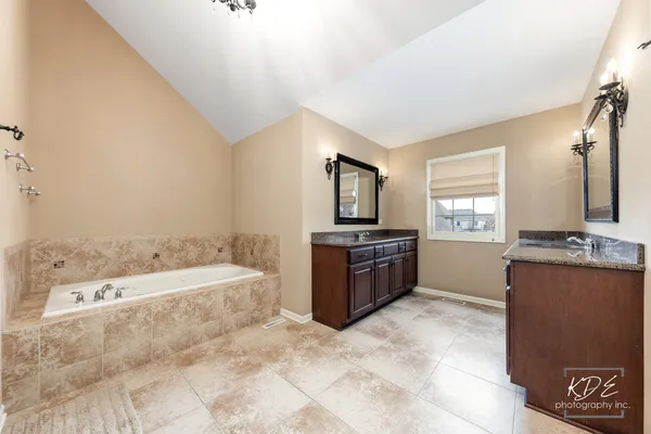 a spacious bathroom with a tub sink and mirror
