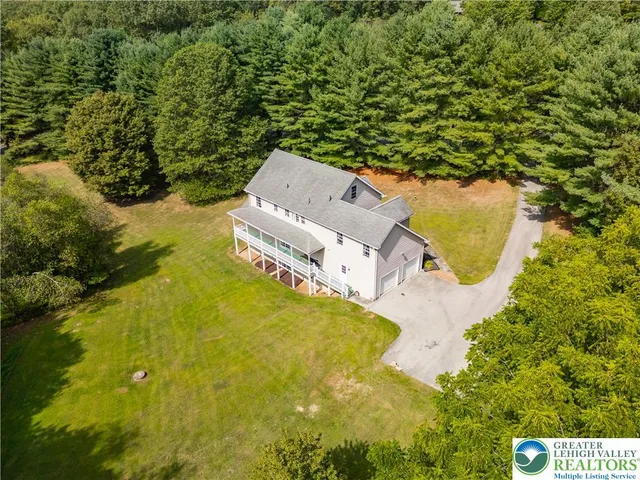 an aerial view of a house with swimming pool and large trees