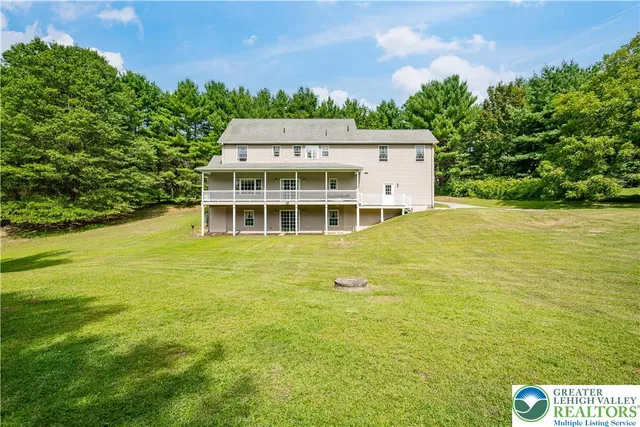 a view of a large pool with lawn chairs and large trees