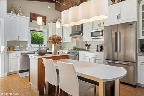 a kitchen with stainless steel appliances a table chairs refrigerator and cabinets