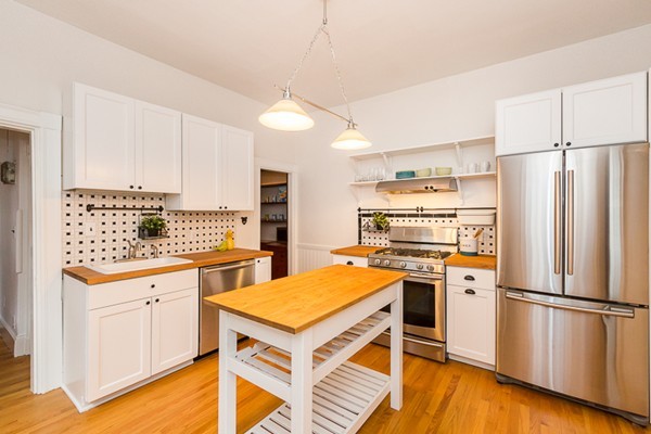 a kitchen with stainless steel appliances a stove a refrigerator and white cabinets