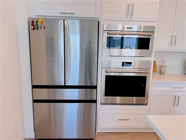 a kitchen with stainless steel appliances a refrigerator a stove and white cabinets