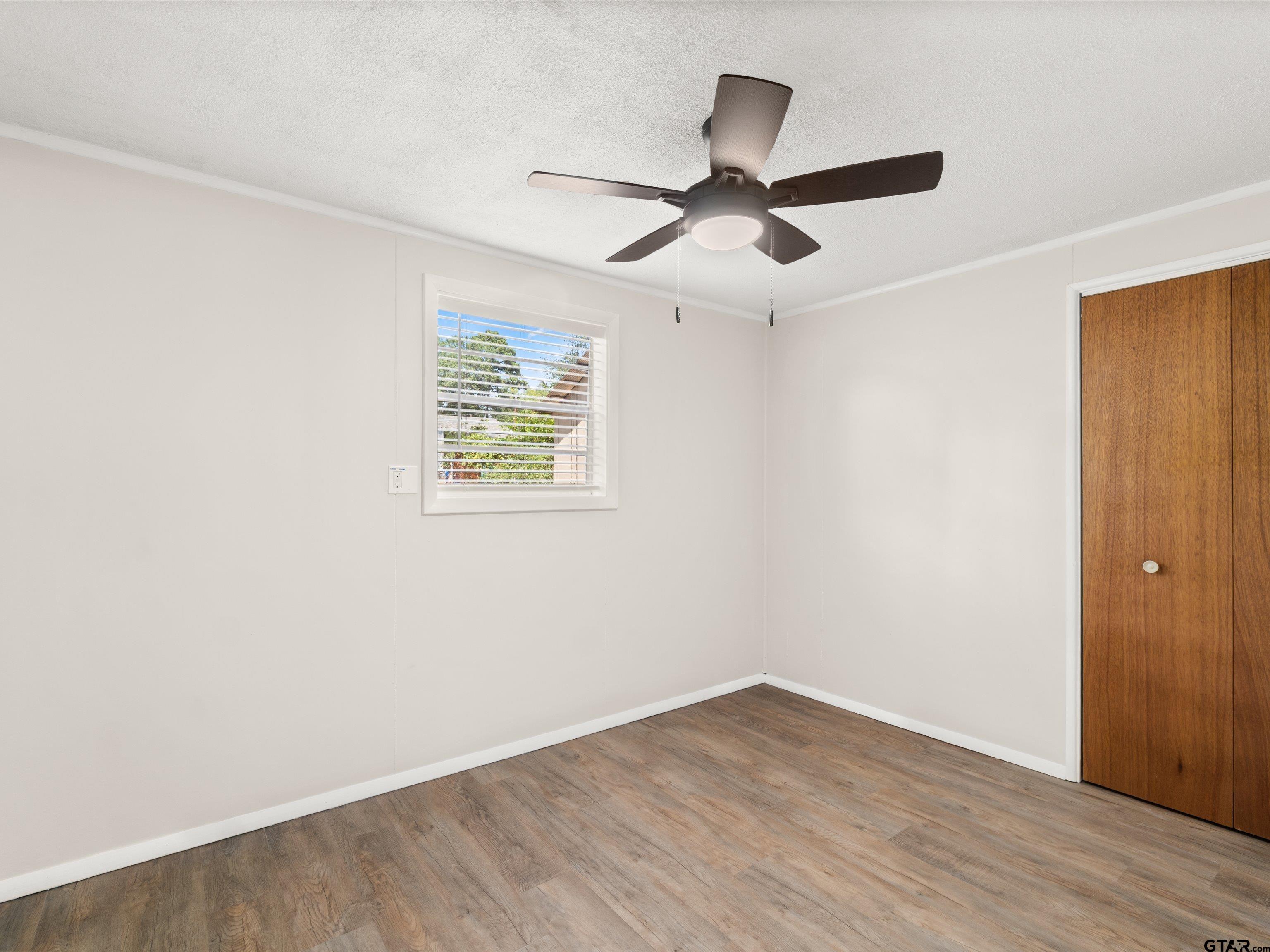 210 Gilbert Street Lone Star, TX 75668 - Photo 17 of 24 an empty room with wooden floor ceiling fan and windows