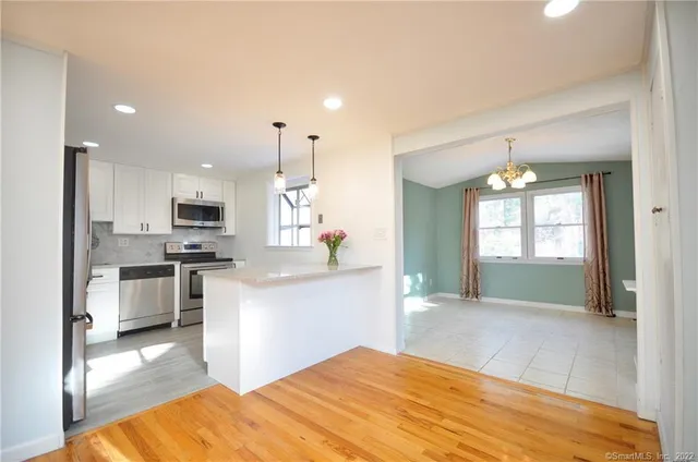 a open kitchen with kitchen island a refrigerator stove microwave and white cabinets